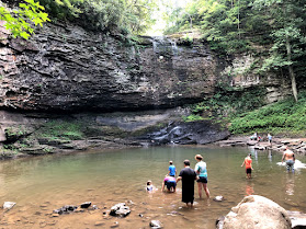Families play in a natural pool at the base of a cliff.